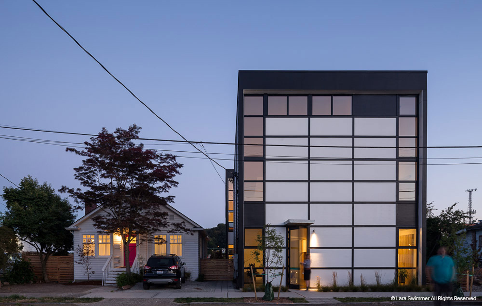Exterior image of office with lots of windows and a man walking towards the camera in motion.