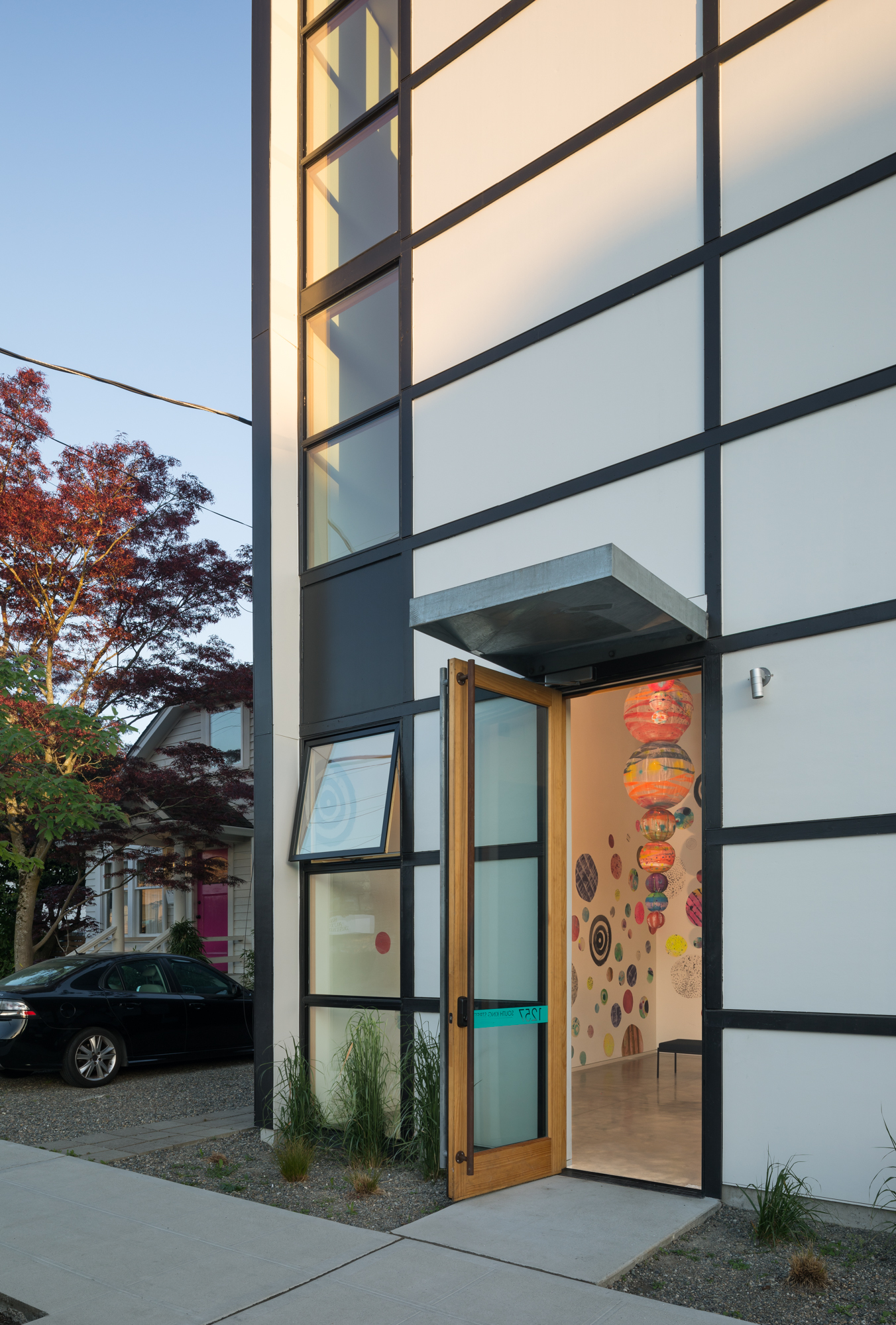 Exterior of office building with their front door open. Office building has a lot of windows.