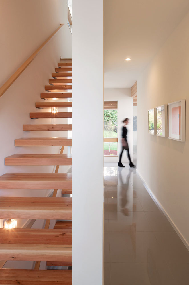 Light wood stairs and person, in motion, moving behind the staircase.