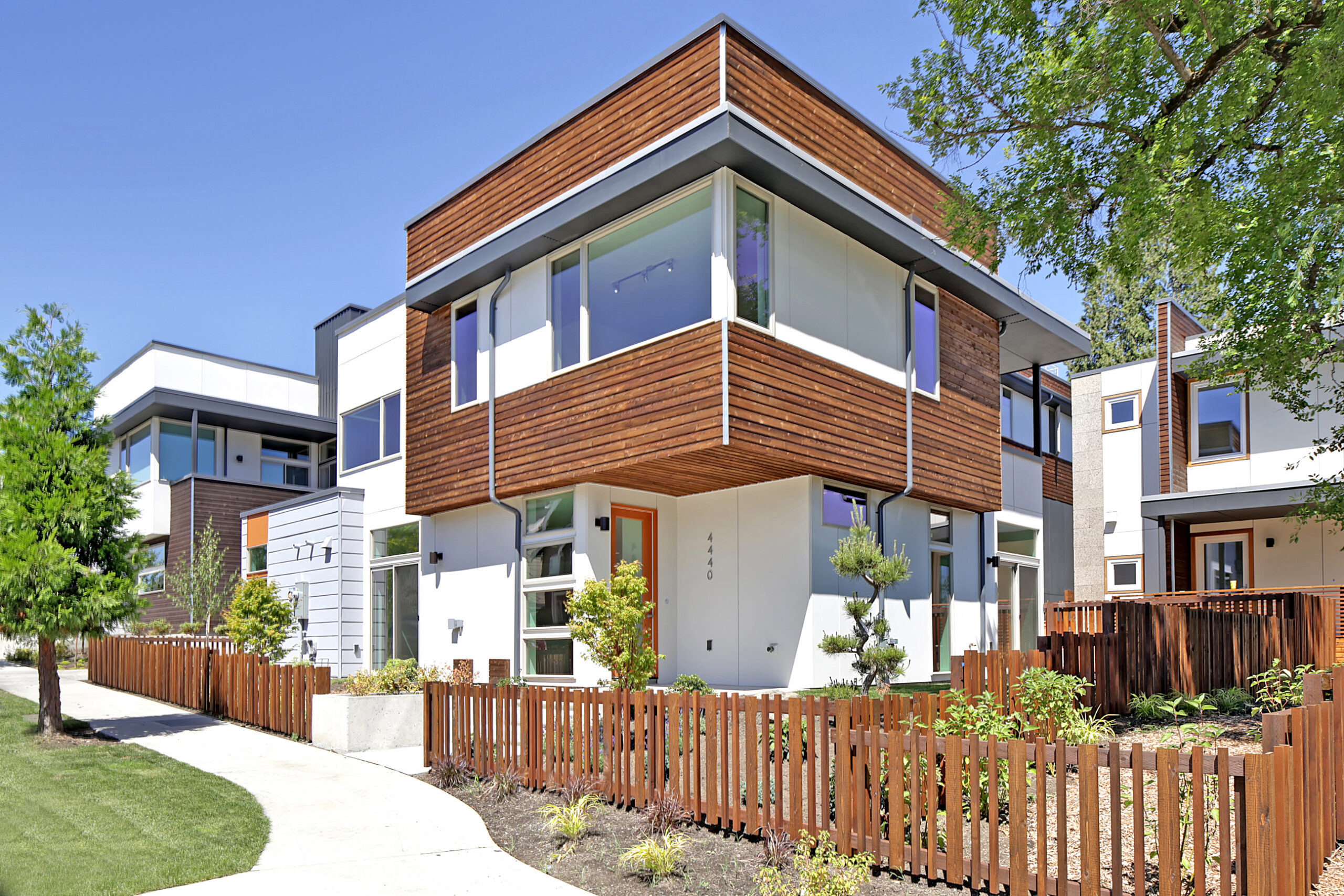 Exterior of one of the residences. This residence is white with wood accents and an orange door.