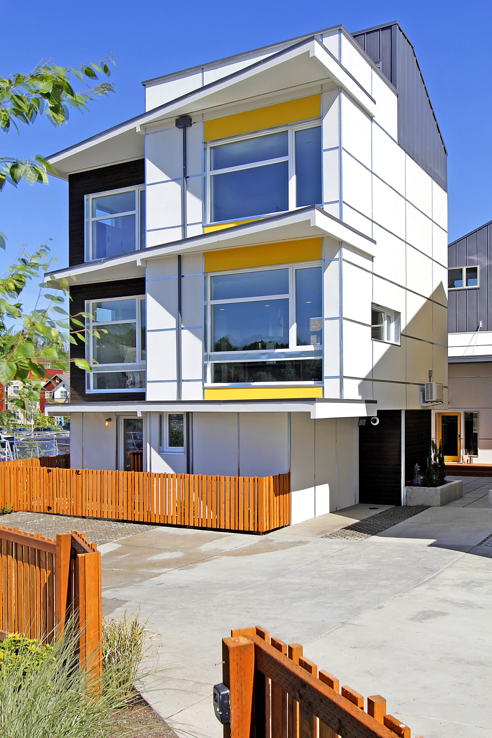Exterior of one residence. The residence is white with lots of windows and yellow accents.