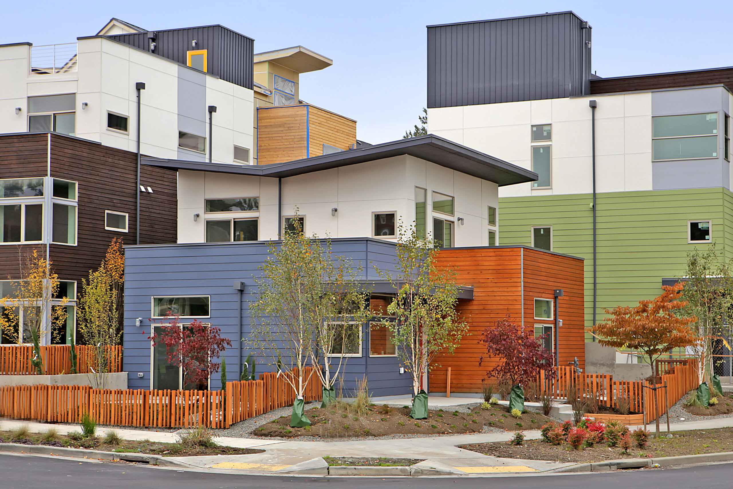 Zoomed out view of residences. Homes are colorful together, some blue, green, orange, white and wood.